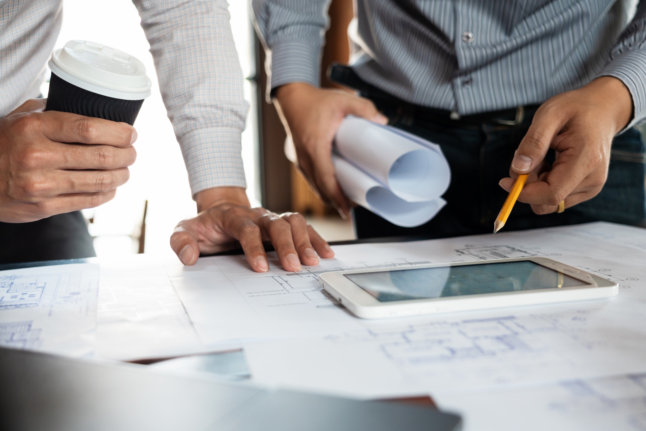 Confident engineer team working with Blue Print with architect equipment discussing and Planning work flow construction project. with partner at the table in office work site.